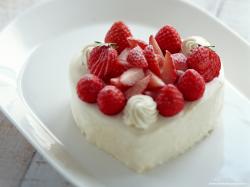 белое пирожное в форме сердечка с красными ягодами